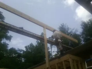 Carpenter setting a ridge beam over a new addition frame — Ice Dam Removal by Roofing Brothers in Riverbank