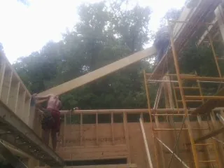 Carpenter raising a rafter beam on a new second story frame in Riverbank