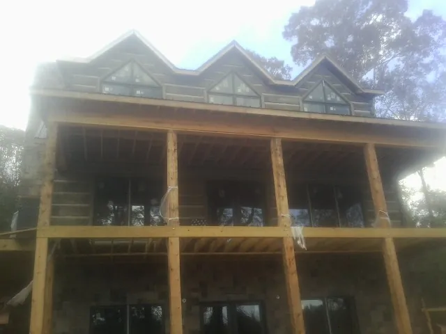 Dormers and porch framing on a large log home under construction — Roof Coating work by our crew in Riverbank