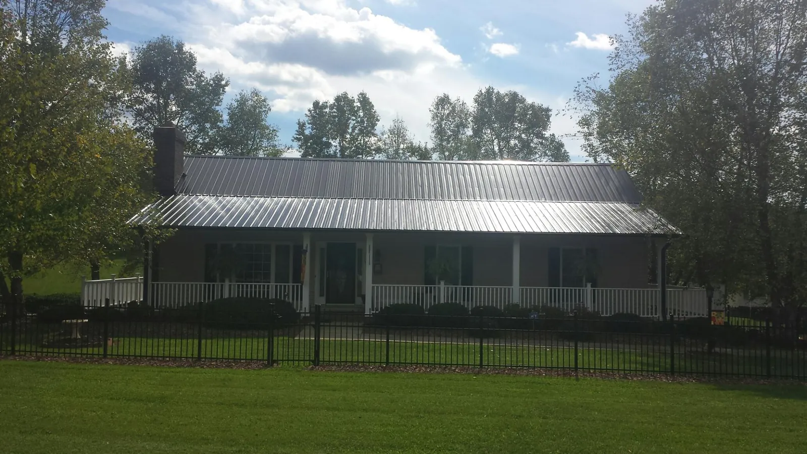 Gray metal roof on a brick ranch with a full width front porch — Gutter Guard Installation work by our crew in Riverbank
