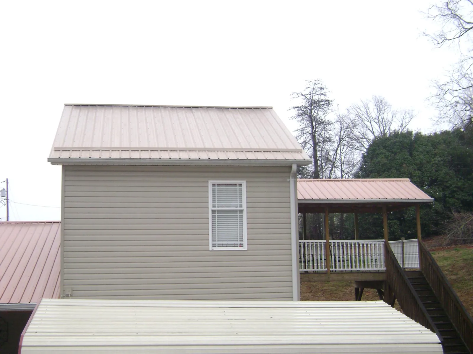 Tan metal roofs on a two story addition and attached porch, from a Roof Replacement job in Riverbank