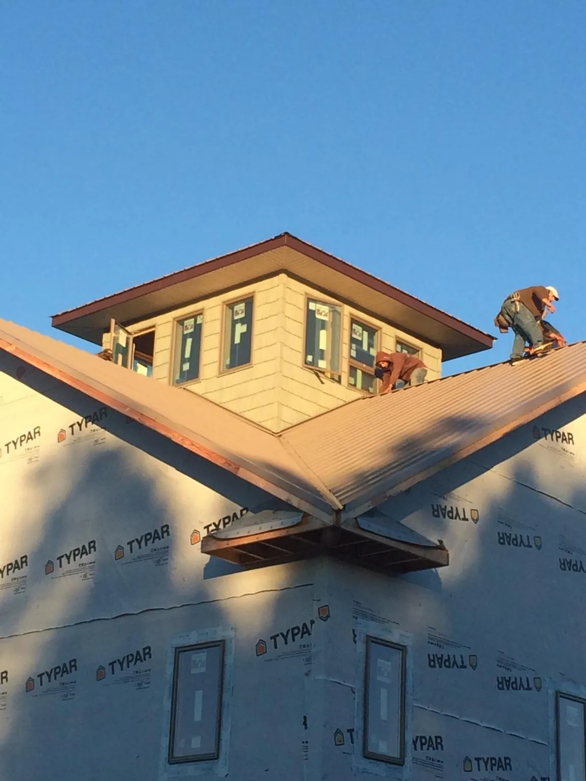 Roofers working around a rooftop cupola on a new metal roof at sunset — Roof Waterproofing in Riverbank by Roofing Brothers